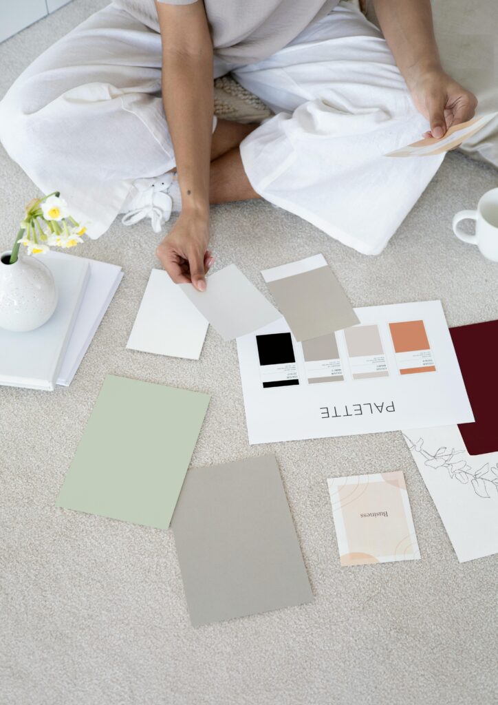 Brand Identity Design service Designer sits on carpet with color palettes and samples, planning creative project.